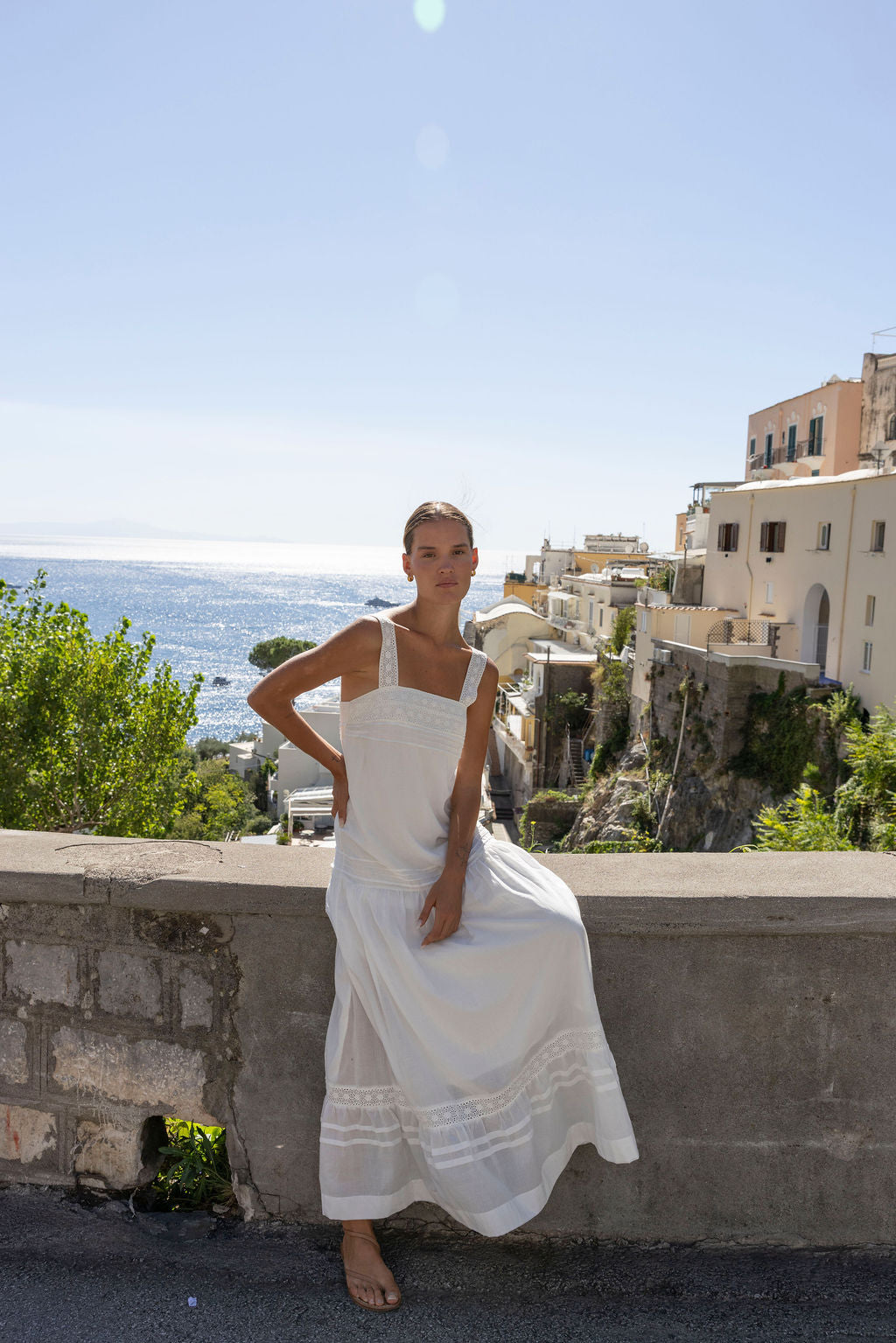 Aurora Maxi Dress, sitting on a wall above the sea in Positano