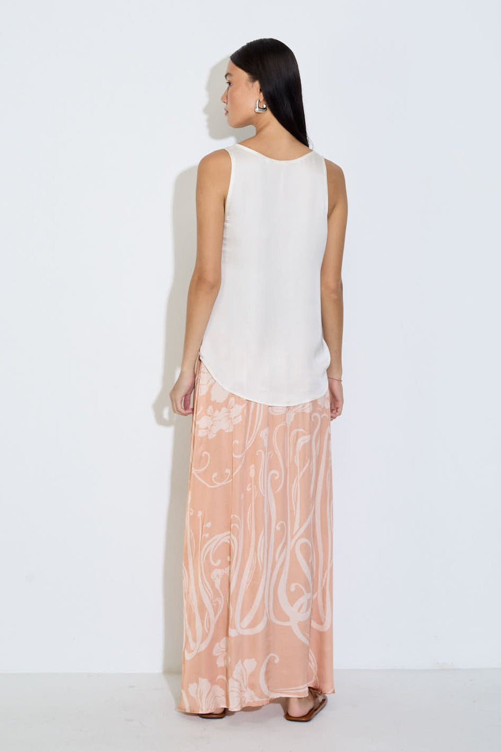Model wearing the Daniella maxi skirt in peach floral viscose satin with elasticated waist