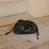 Black woven leather Naomi Clutch on a wooden bench on the Nusa islands