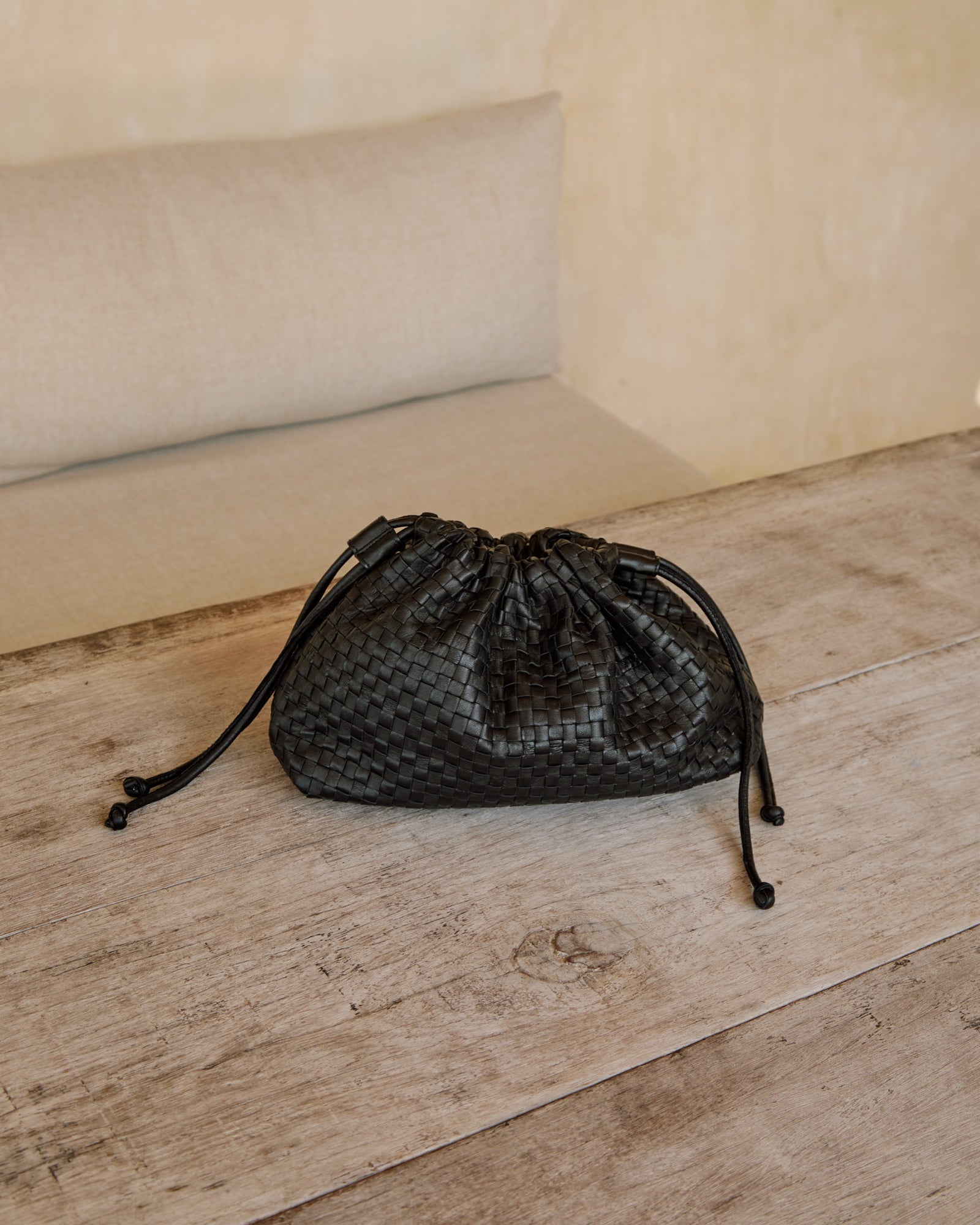 Black woven leather Naomi Clutch on a wooden bench on the Nusa islands