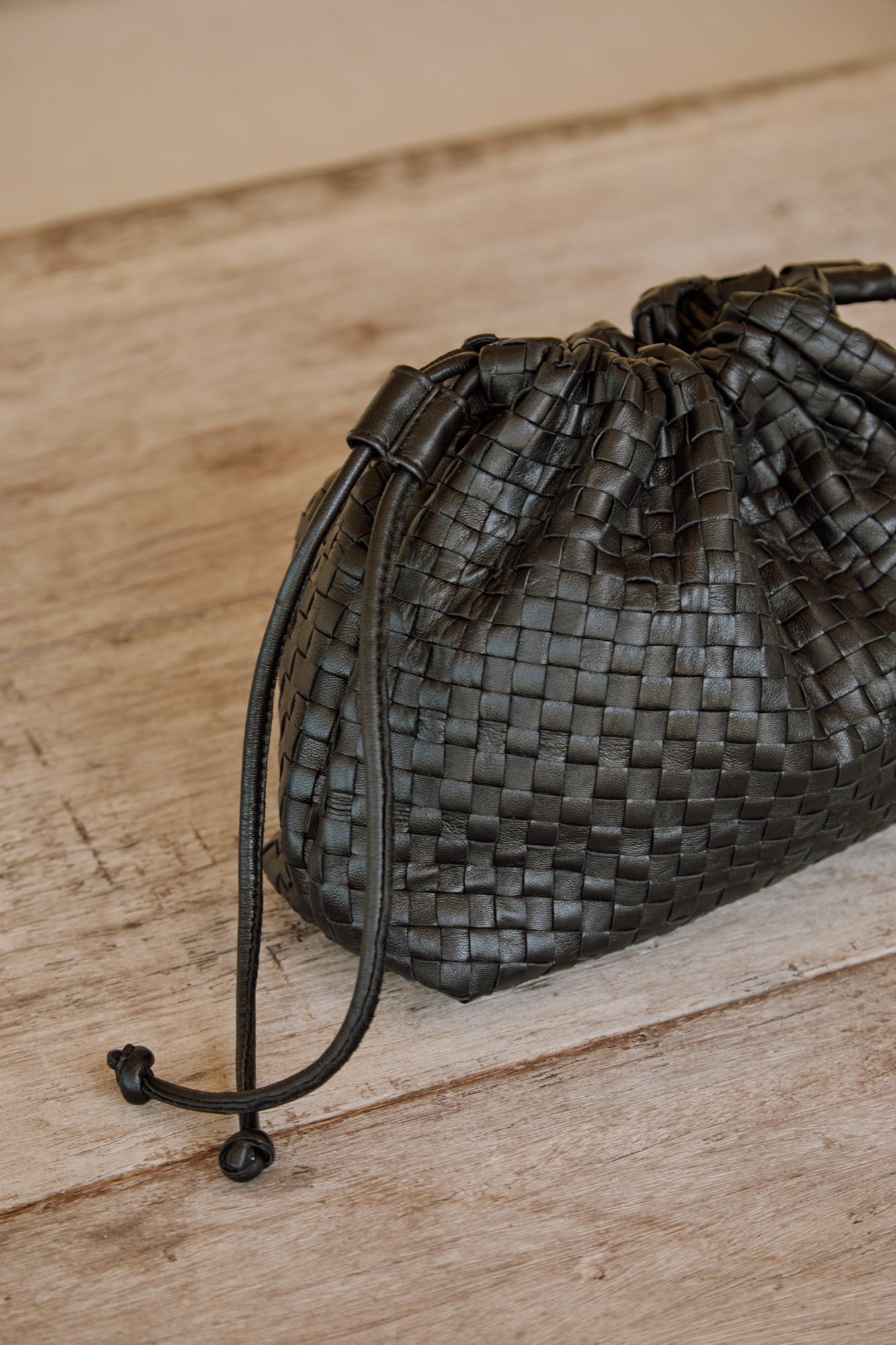 Close-up of the black woven leather Naomi Clutch with its leather drawstring